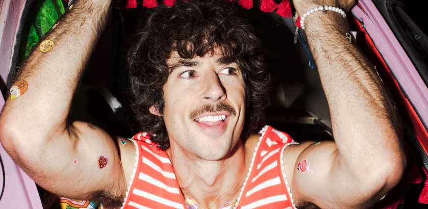 Photo of Australian music artist Go-Jo. He is wearing a red and white striped sleeveless shirt and has his arms raised.