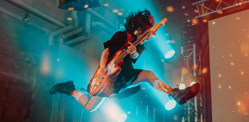Musician playing guitar is pictured in mid-air.