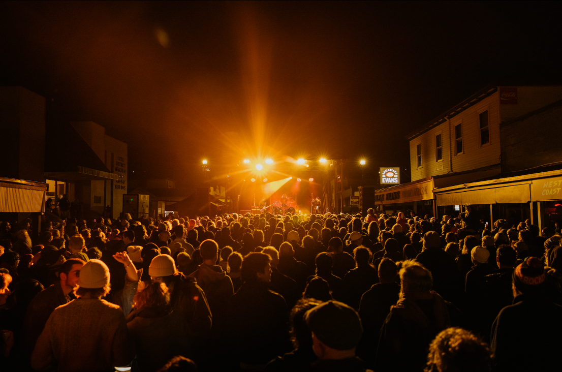 A crowd of people in the street watching Spiderbait perform on stage in Tasmania.