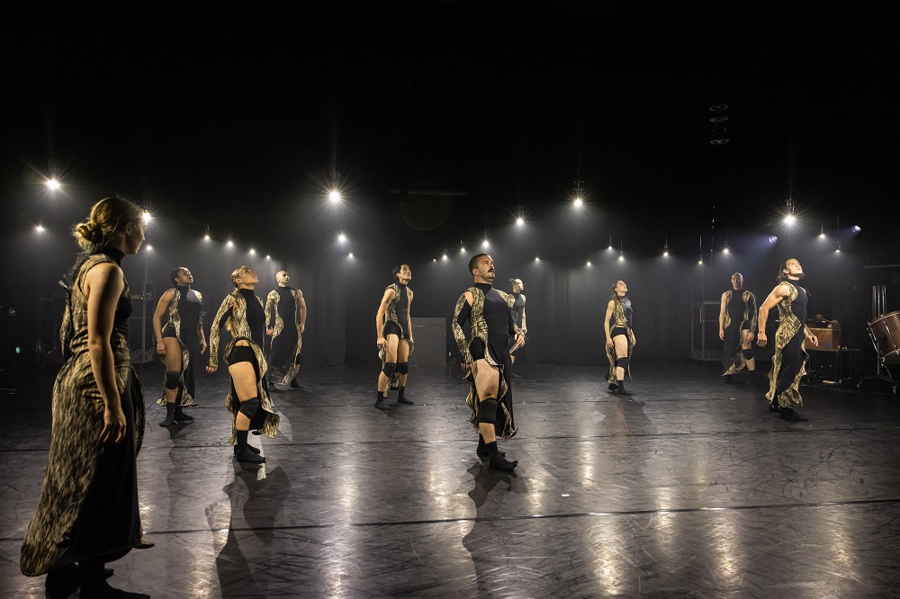 Ten dancers on stage performing a contemporary dance routine.