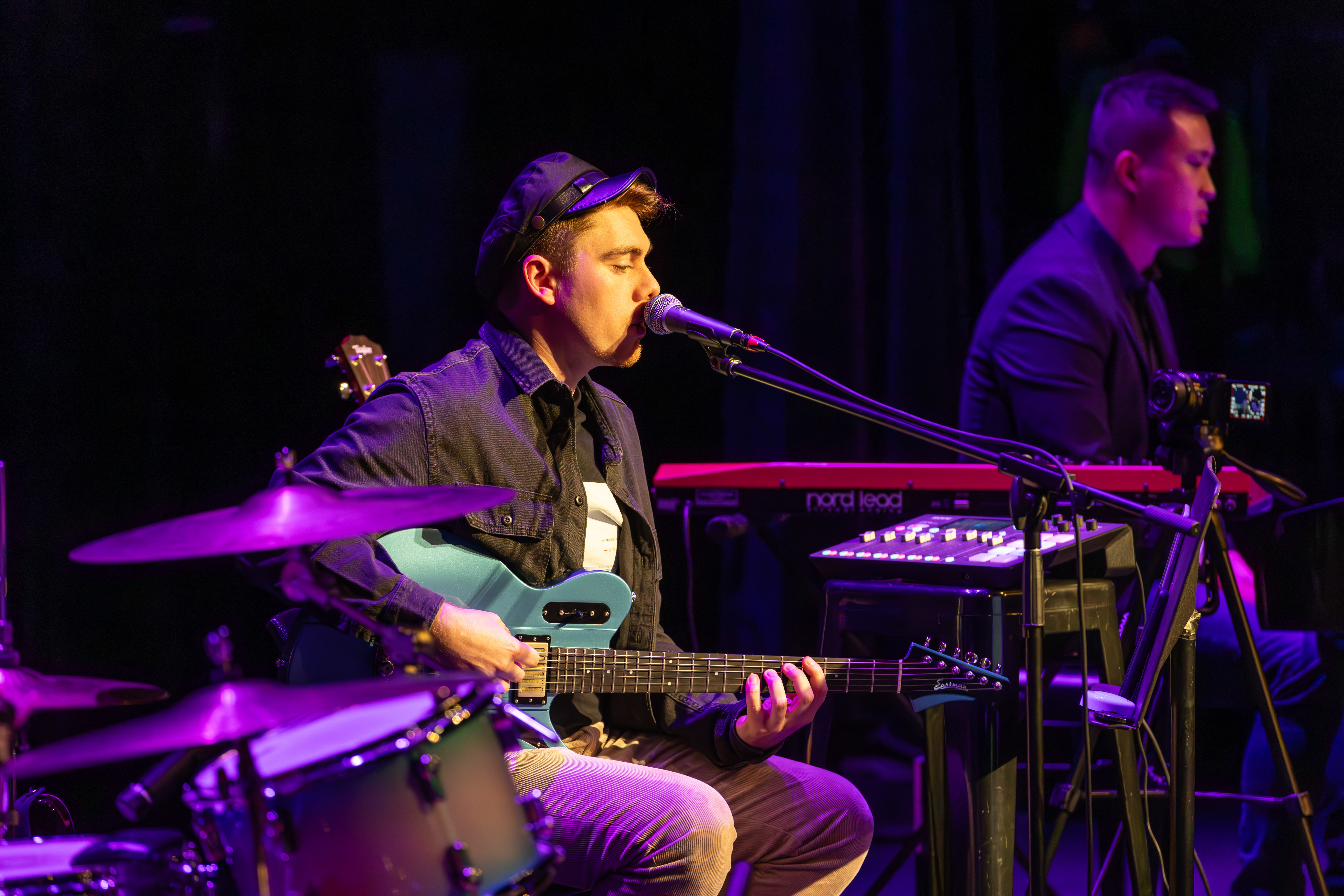 Man playing guitar and singing into a microphone.