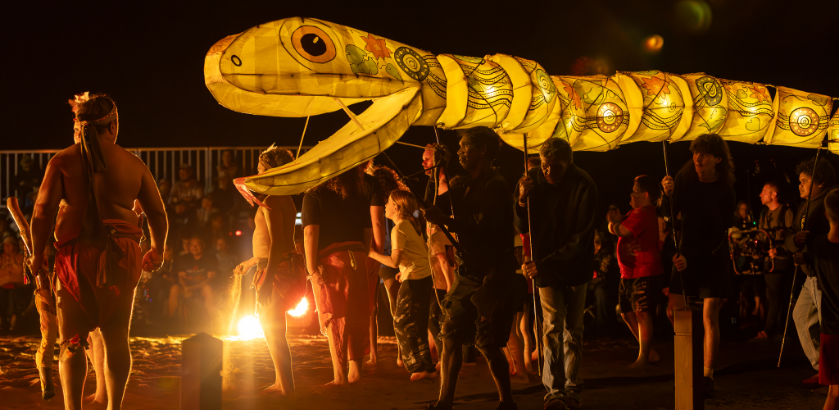 Moonda Nurra performance at Festival of Outback Skies in Hughenden, Queensland. A large golden puppet snake is shown over a crowd at night.