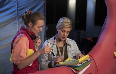 Two people on a set reviewing paperwork.