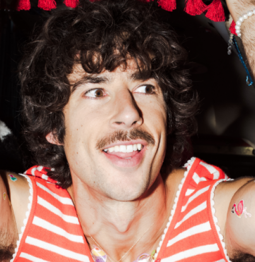 Photo of Australian music artist Go-Jo. He is wearing a red and white striped sleeveless shirt and has his arms raised.