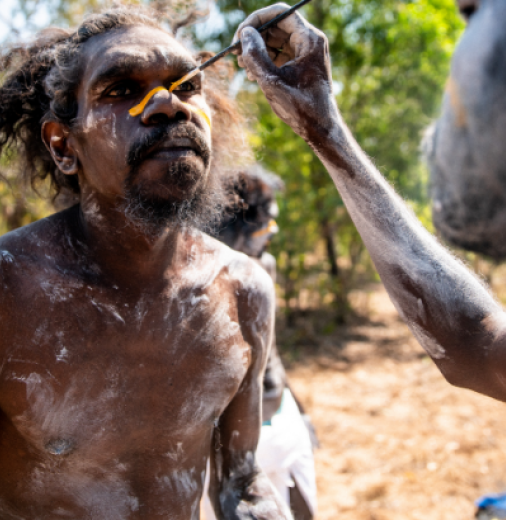 Clan junggay (Cultural leader from opposite moiety) being painted up for Mun-jiburay bunggul (performance). The yellow line represents the Balkarranga clan totem Rajarra (Barramundi).