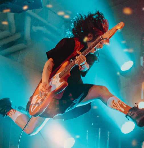 Musician playing guitar is pictured in mid-air.