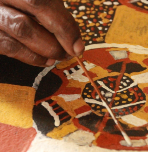 First Nations woman painting a picture on table