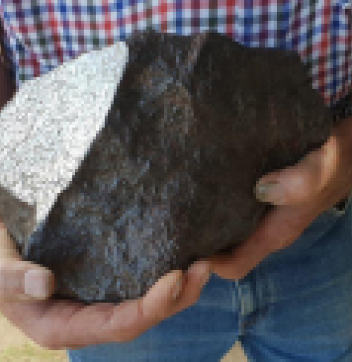 Man holding the Georgetown iron meteorite. It fits in both of his hands and is quite large.