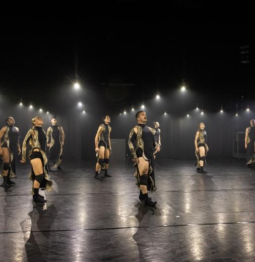 Ten dancers on stage performing a contemporary dance routine.