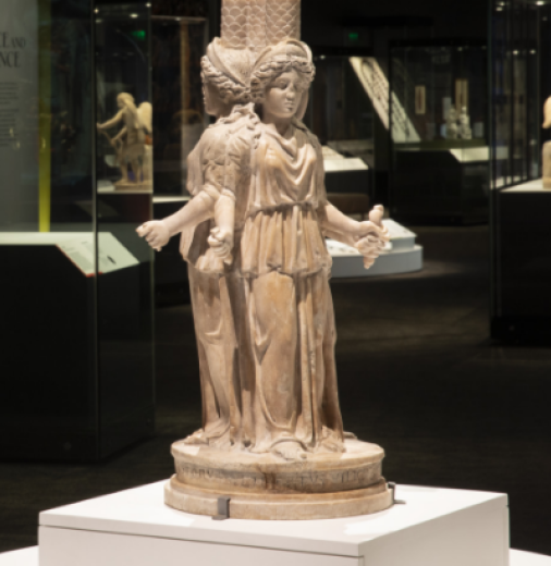 Ancient statue of the Roman goddess Hekate stands on a plinth in a display space. 