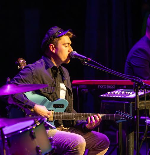 Man playing guitar and singing into a microphone.