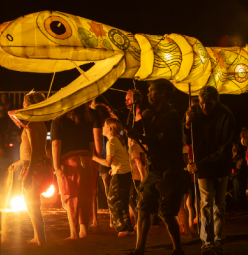 Moonda Nurra performance at Festival of Outback Skies in Hughenden, Queensland. A large golden puppet snake is shown over a crowd at night.