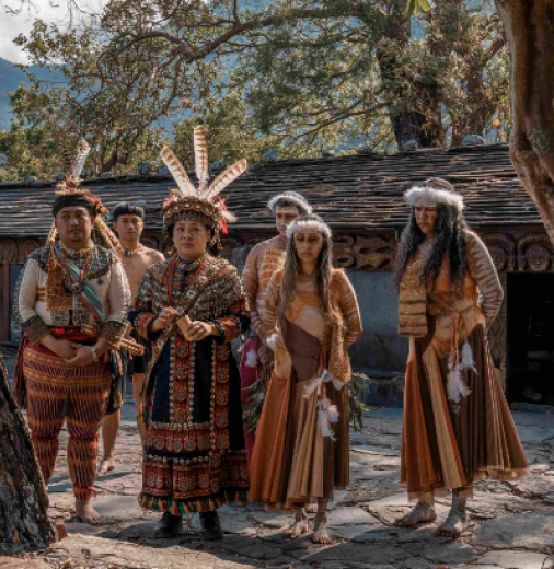 Taiwanese and First Nations Australian performers next to a stone hut. 