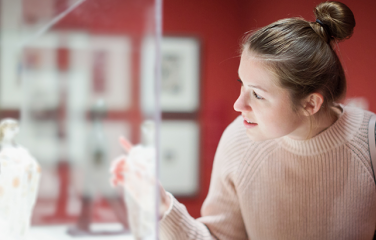 image of a woman looking into a glass museum cabinet
