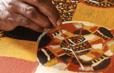 First Nations woman painting a picture on table