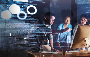 Three tech developers are looking at a computer screen. 