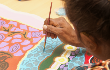 A woman paints on a canvas.